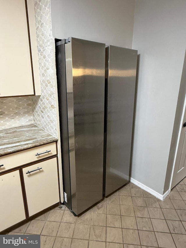 kitchen featuring white cabinetry, backsplash, and stainless steel fridge