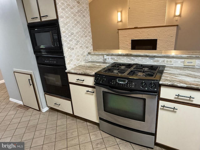 kitchen with backsplash, light stone counters, black appliances, light tile patterned floors, and white cabinetry