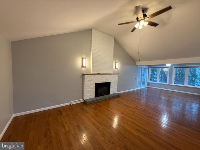 unfurnished living room featuring dark hardwood / wood-style flooring, vaulted ceiling, a stone fireplace, and ceiling fan