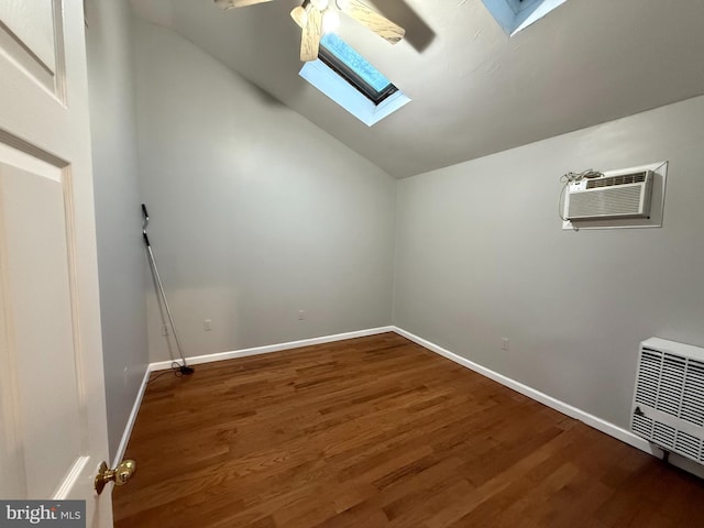 additional living space with vaulted ceiling with skylight, wood-type flooring, and a wall mounted AC