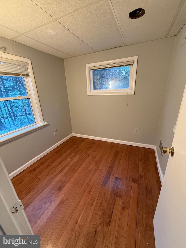 unfurnished room with hardwood / wood-style floors and a drop ceiling