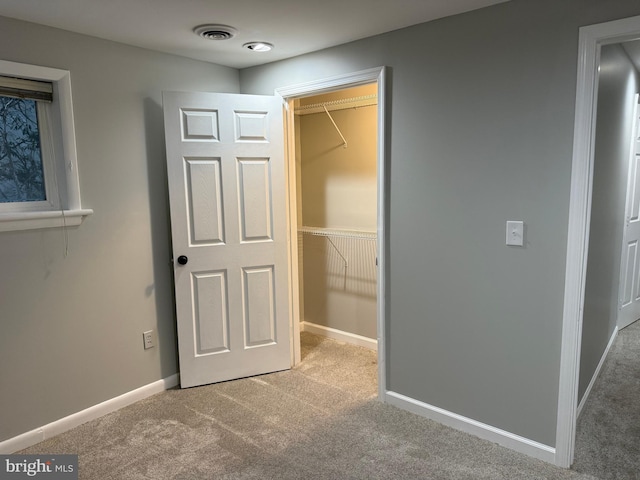 unfurnished bedroom with light carpet, a spacious closet, and a closet