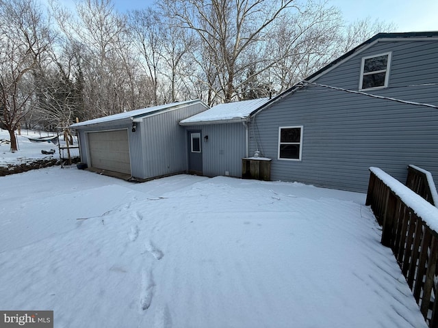 snow covered rear of property featuring a garage