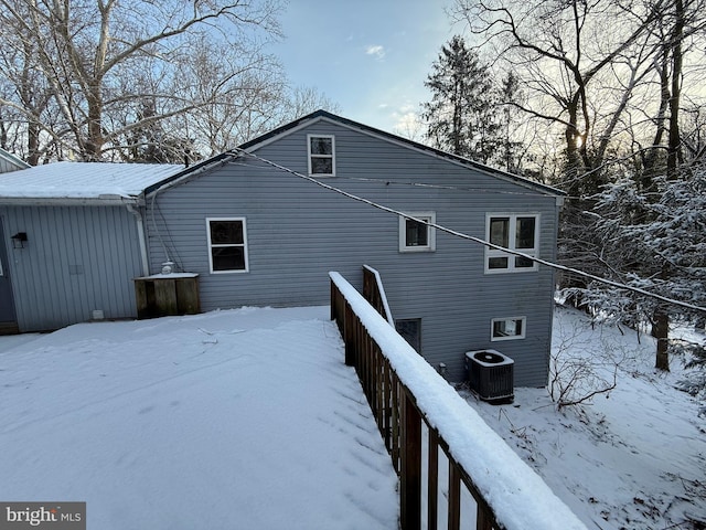 snow covered rear of property featuring central AC unit