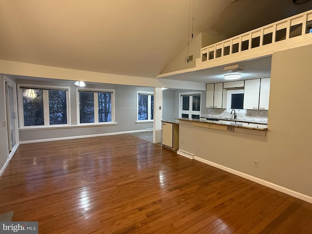 kitchen with dark hardwood / wood-style floors, sink, backsplash, and high vaulted ceiling