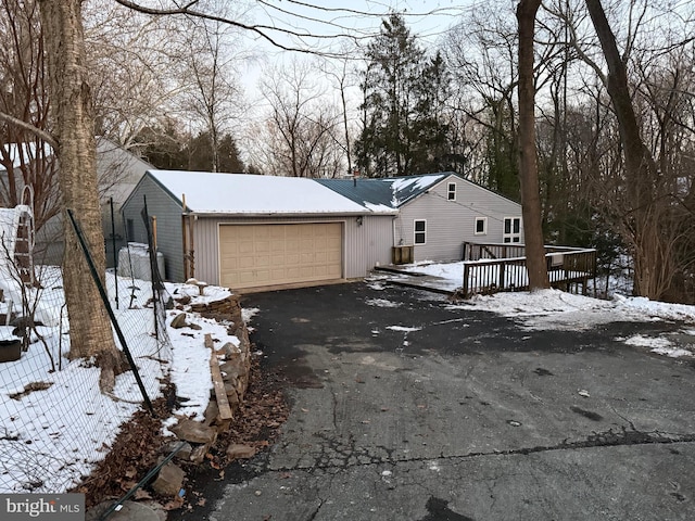 view of snowy exterior featuring a garage and a wooden deck