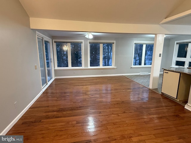 unfurnished living room featuring lofted ceiling and dark wood-type flooring