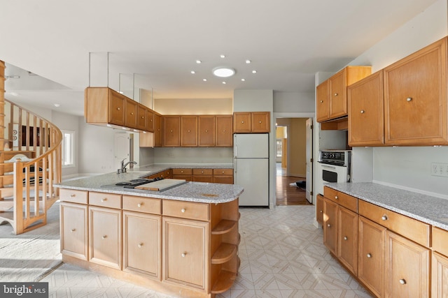 kitchen featuring light stone counters, white appliances, and sink