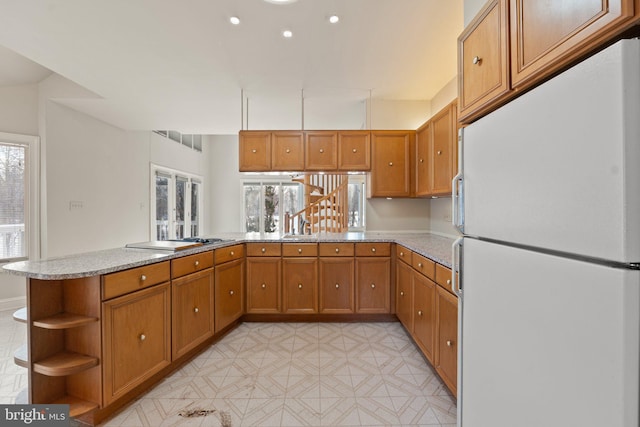 kitchen featuring kitchen peninsula, stainless steel gas stovetop, and white refrigerator