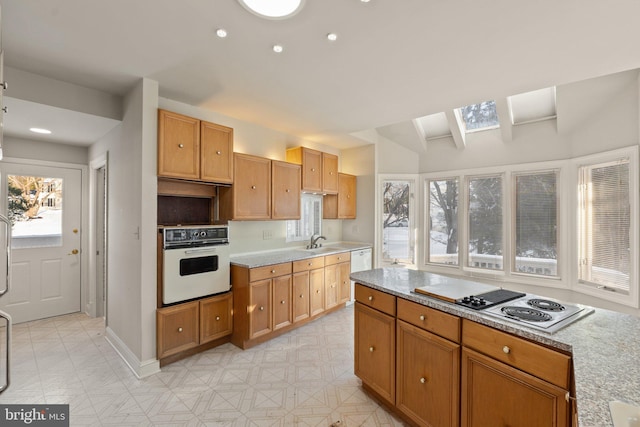 kitchen featuring white appliances, lofted ceiling with skylight, a wealth of natural light, and sink