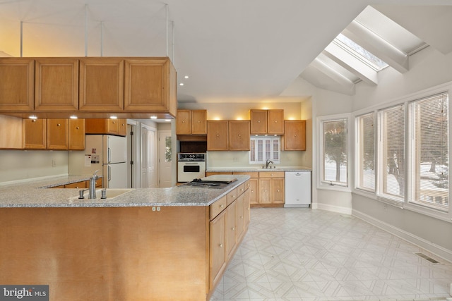 kitchen with white appliances, light stone counters, lofted ceiling with skylight, and sink