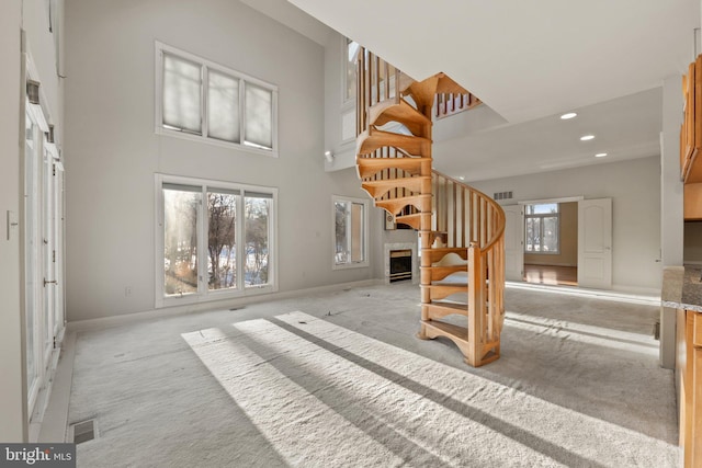 interior space featuring carpet, a high ceiling, and a fireplace