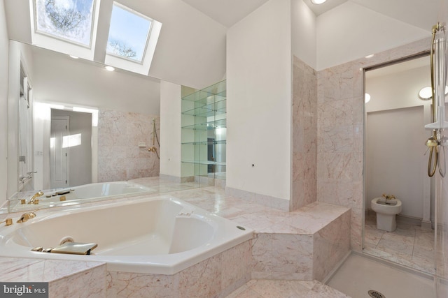 bathroom featuring a skylight, a bidet, and tiled tub