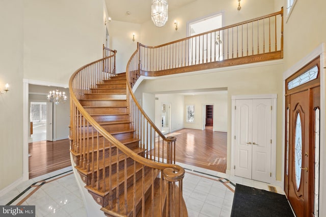 entrance foyer with light tile patterned flooring, a towering ceiling, and an inviting chandelier