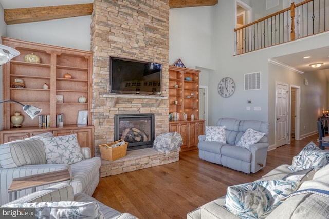 living room with light wood-type flooring, a fireplace, beamed ceiling, and a high ceiling