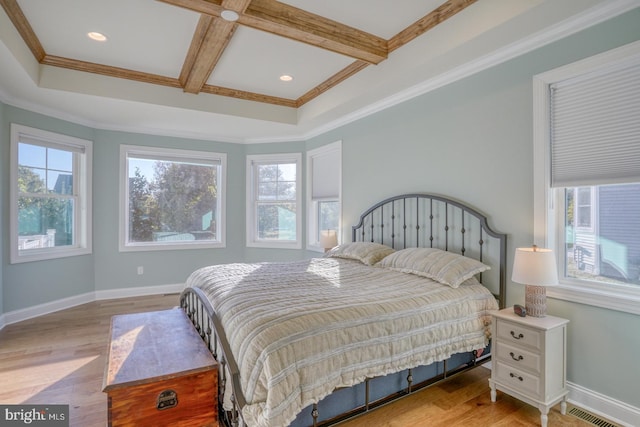 bedroom featuring crown molding, light hardwood / wood-style flooring, coffered ceiling, and multiple windows