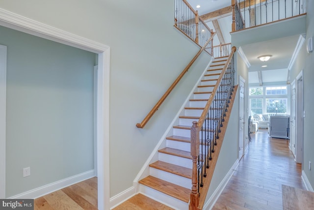 stairway with hardwood / wood-style flooring and ornamental molding