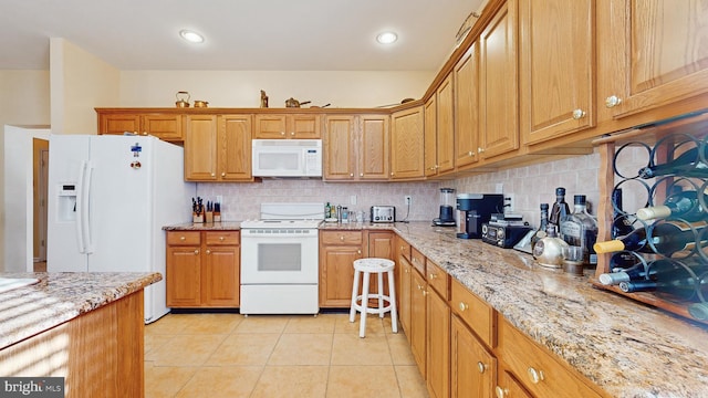 kitchen featuring light stone counters, light tile patterned floors, white appliances, and decorative backsplash