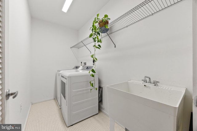 laundry area featuring washing machine and dryer, light tile patterned floors, and sink