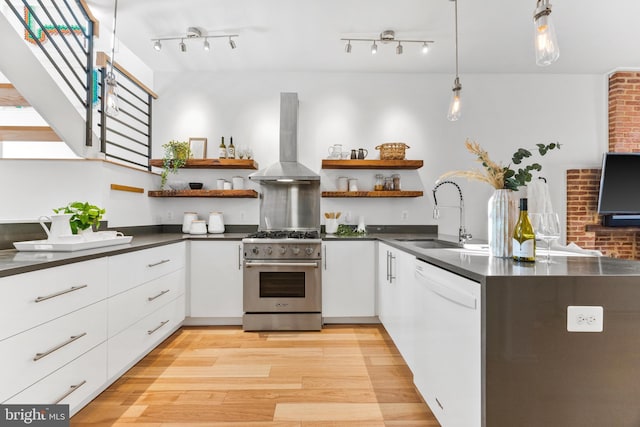 kitchen featuring stainless steel range, white dishwasher, wall chimney exhaust hood, white cabinets, and sink