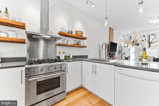 kitchen featuring white cabinets, wall chimney exhaust hood, light hardwood / wood-style floors, white dishwasher, and gas stove