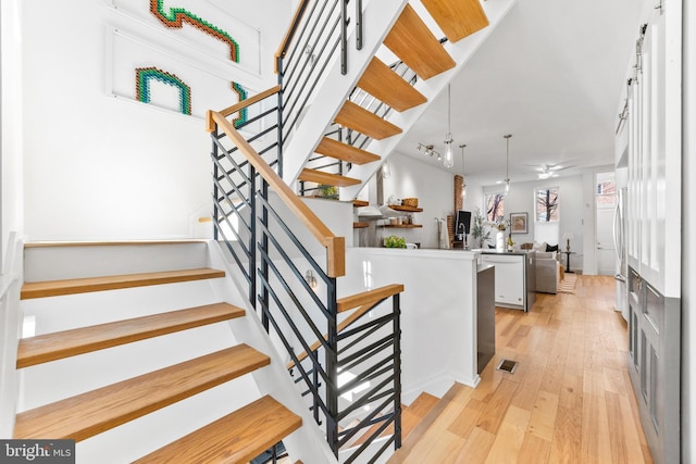 stairs with ceiling fan and hardwood / wood-style flooring