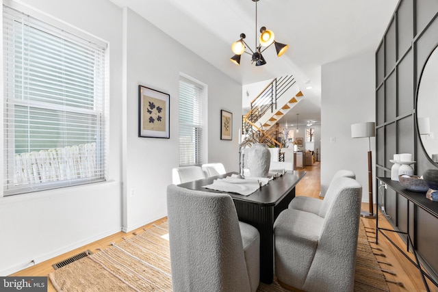 dining area with light hardwood / wood-style floors, a notable chandelier, and plenty of natural light