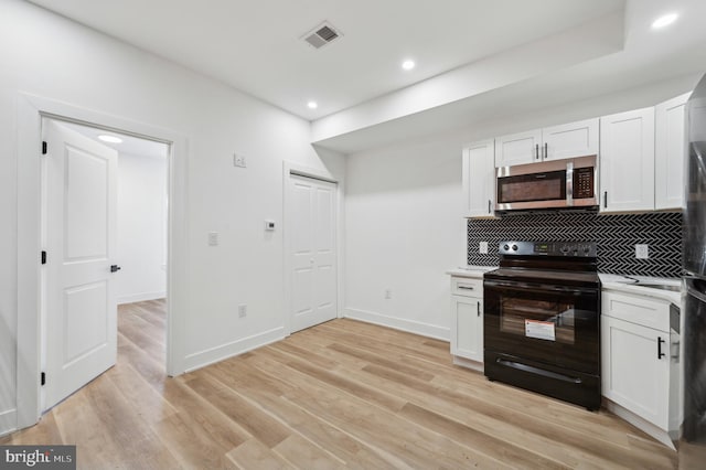 kitchen featuring white cabinetry, black electric range oven, and tasteful backsplash