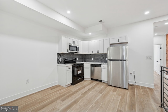 kitchen with white cabinets, light wood-type flooring, stainless steel appliances, and tasteful backsplash