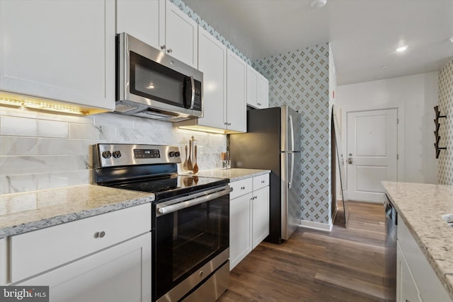 kitchen with white cabinets, dark hardwood / wood-style floors, light stone countertops, tasteful backsplash, and stainless steel appliances