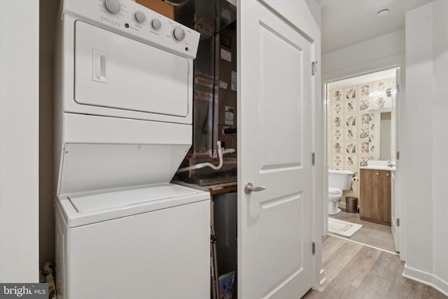 washroom featuring stacked washer / dryer and light hardwood / wood-style flooring