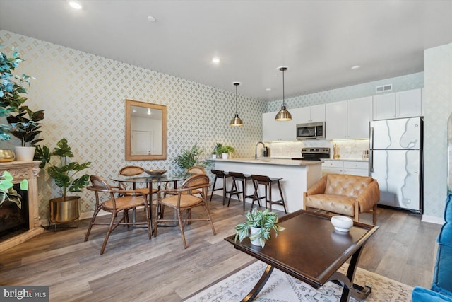 living room with a tile fireplace, light hardwood / wood-style flooring, and sink