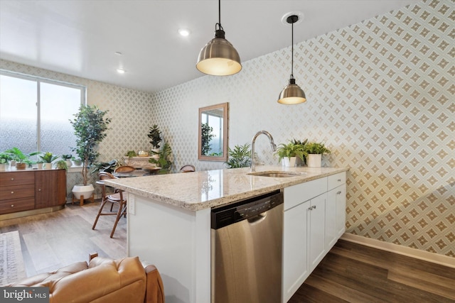 kitchen featuring light stone countertops, white cabinetry, dishwasher, hanging light fixtures, and sink