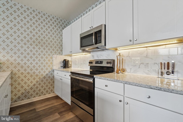 kitchen featuring dark wood-type flooring, decorative backsplash, appliances with stainless steel finishes, light stone counters, and white cabinetry