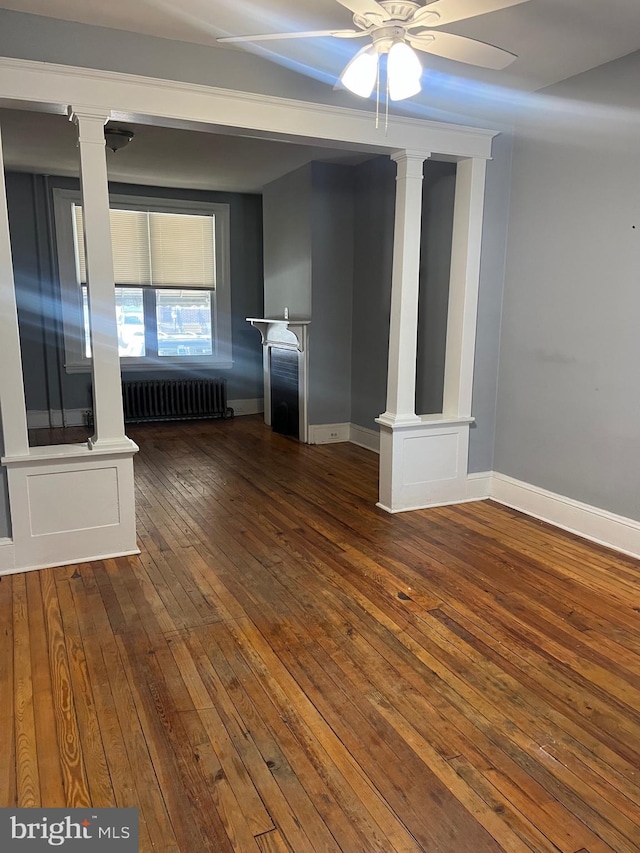 empty room featuring dark hardwood / wood-style flooring, radiator, and ceiling fan