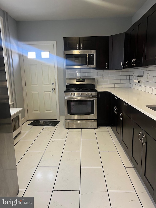 kitchen with decorative backsplash, light tile patterned floors, sink, and appliances with stainless steel finishes