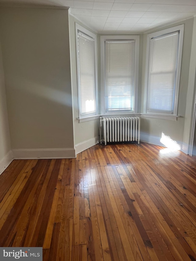 spare room with hardwood / wood-style flooring and radiator heating unit