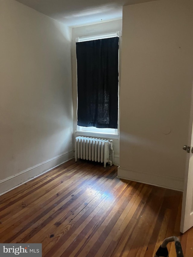 unfurnished room featuring hardwood / wood-style flooring and radiator