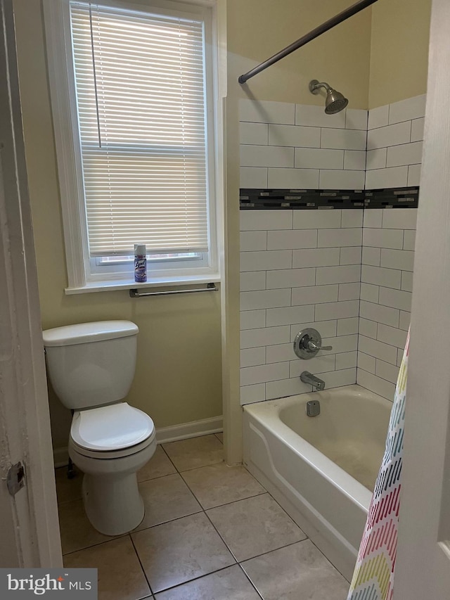 bathroom featuring tile patterned flooring, tiled shower / bath, and toilet