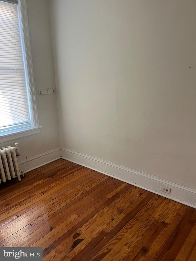 empty room featuring wood-type flooring and radiator