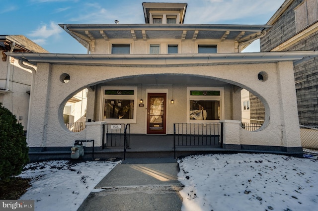 snow covered property entrance with covered porch