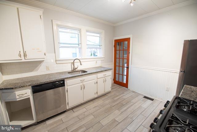 kitchen with white cabinets, appliances with stainless steel finishes, light hardwood / wood-style flooring, and sink