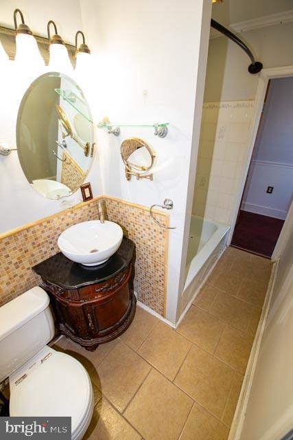 bathroom with toilet, tile patterned floors, backsplash, a shower, and vanity