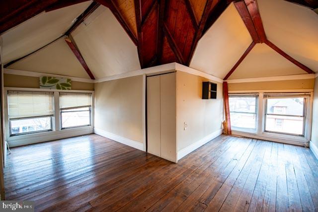 empty room with dark hardwood / wood-style flooring, high vaulted ceiling, and plenty of natural light