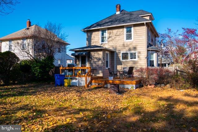 rear view of property featuring a lawn and a wooden deck