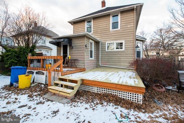 snow covered house with a wooden deck