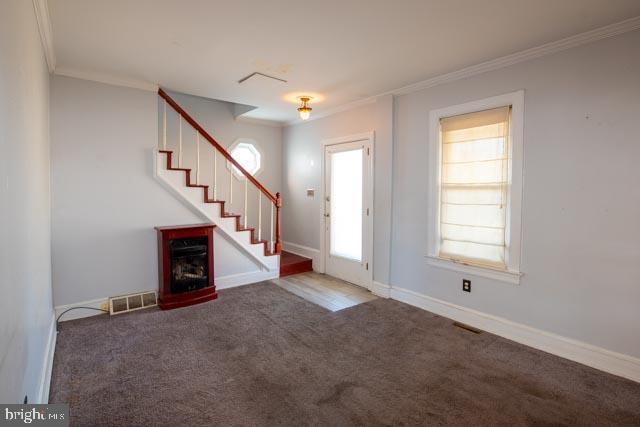 entrance foyer with carpet, a healthy amount of sunlight, and crown molding