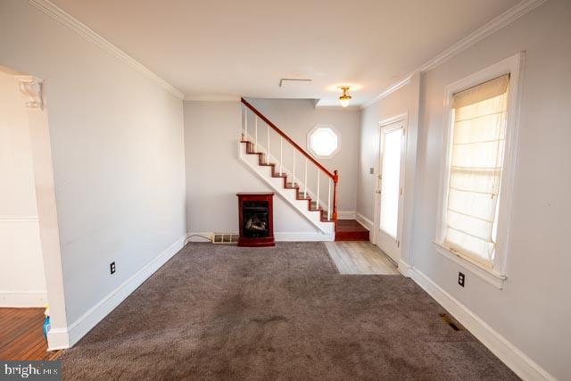 foyer with carpet flooring, a wealth of natural light, and crown molding