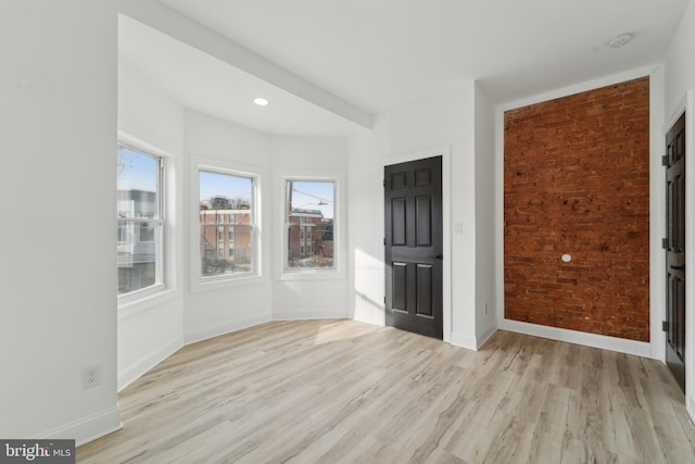 interior space with light hardwood / wood-style floors and brick wall