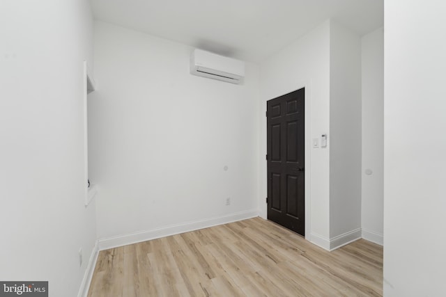 empty room featuring a wall unit AC and light wood-type flooring